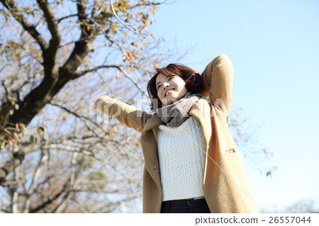 A woman stretching by wearing a coat 26557044