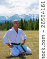 Man in kimono meditating on mountains background. 26564161