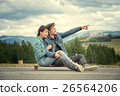 The guy with girl sit on a longboard. Man shows 26564206