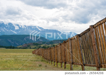 Long wooden fence in a field. In the distance the Long wooden fence in a field. In the distance the 26564208