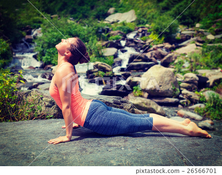 Woman practices yoga asana Urdhva Mukha Svanasana 26566701