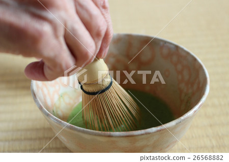 Whip matcha in a pink Hagi tea bowl on a tatami mat, holding a chasen in your right hand. Whip matcha in a pink Hagi tea bowl on a tatami mat, holding a chasen in your right hand. 26568882