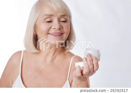 Pleasant senior woman looking at the cream bottle 26592817