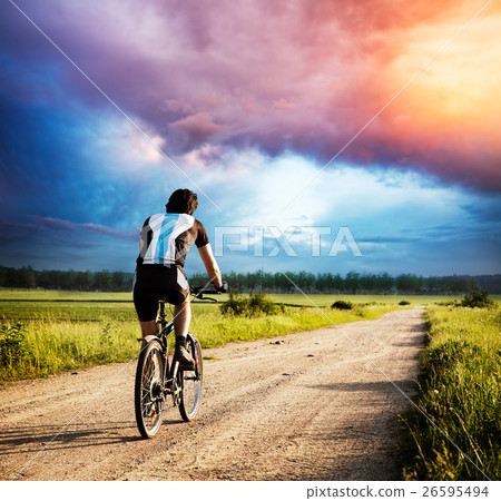 Man Riding a Bike on Country Road at Sunset 26595494