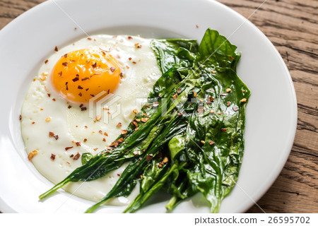 Fried egg with spinach on the wooden table Fried egg with spinach on the wooden table 26595702