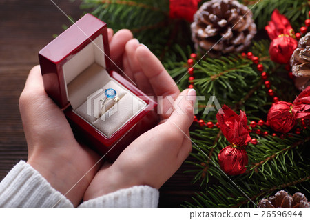 Engagement ring in female hands among Christmas Engagement ring in female hands among Christmas 26596944