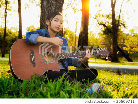 Woman playing guitar in park 26609711