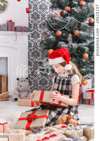 Beautiful girl in santa hat unwrapping christmas 26628197