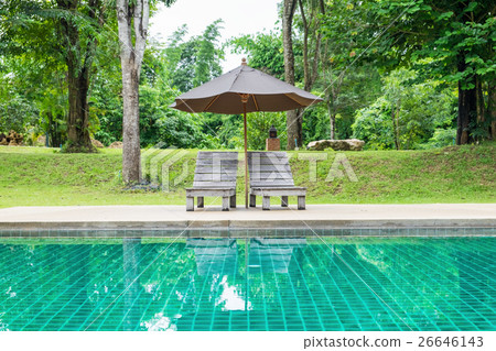 Wooden sunbed with umbrella on modern pool 26646143