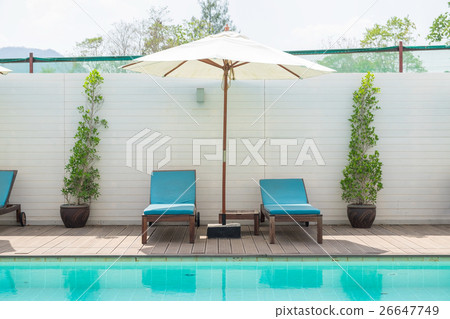 Blue sunbed with white umbrella by pool 26647749