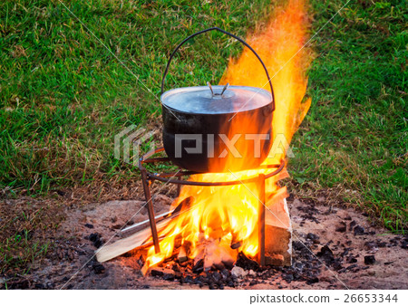 On a fire there is a pan in the food is cooked. On a fire there is a pan in the food is cooked. 26653344
