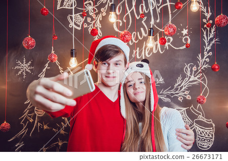 Happy couple in funny hats standing hugging and 26673171