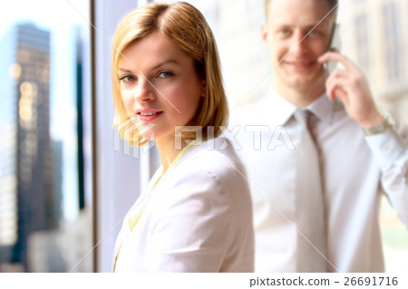 business woman and man standing near window business woman and man standing near window 26691716