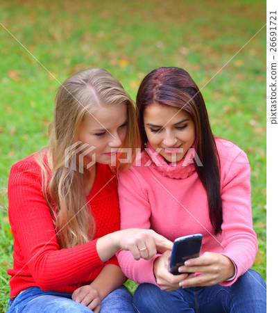 Two girls in park with a mobile phone 26691721