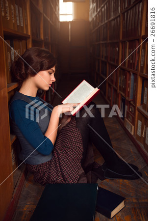 Teenager sitting on a floor of library and read. Teenager sitting on a floor of library and read. 26691816