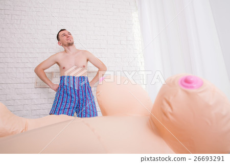 Man stay near the bed with inflatable sex doll. Stock Photo