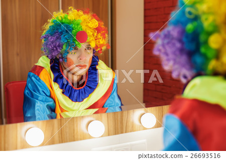 Circus clown looks in a mirror in makeup room. Circus clown looks in a mirror in makeup room. 26693516