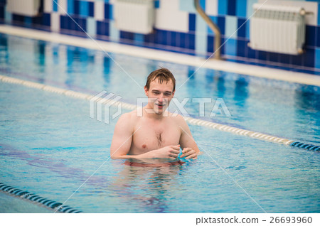 Young happy man in the swimming pool gesturing Young happy man in the swimming pool gesturing 26693960