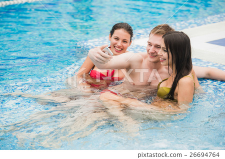 three friends taking selfie in the swimming pool three friends taking selfie in the swimming pool 26694764