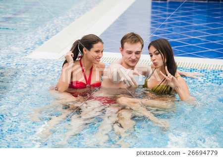 three friends taking selfie in the swimming pool three friends taking selfie in the swimming pool 26694779