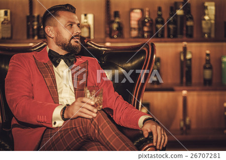 Extravagant stylish man with whisky glass sitting 26707281