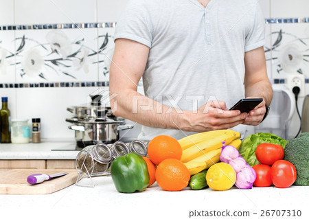 Using smartphone in the kitchen by healthy man Using smartphone in the kitchen by healthy man 26707310