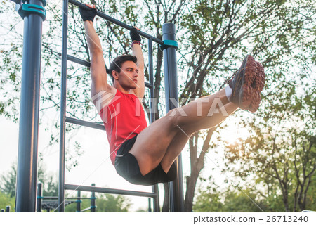 Fitnes man hanging on wall bars performing legs Fitnes man hanging on wall bars performing legs 26713240