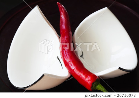 Broken white cup, red paprika, black background 26716078