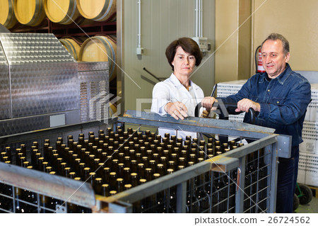Expert and wine maker inspect containers with bottles 26724562