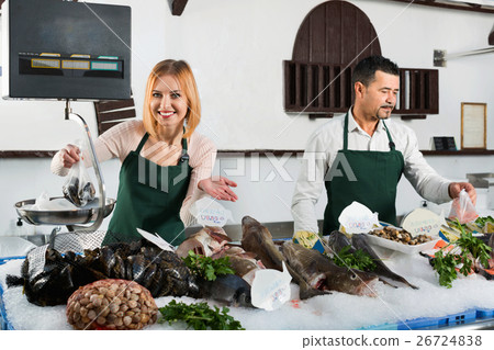 Shop employee selling fresh fish and chilled seafood 26724838