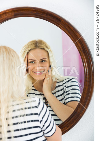Cute girl watching herself in mirror indoors Cute girl watching herself in mirror indoors 26724995