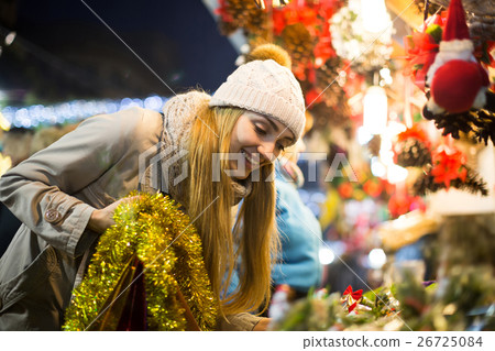 Portrait of woman in coat posing at Xmas fair in evening Portrait of woman in coat posing at Xmas fair in evening 26725084