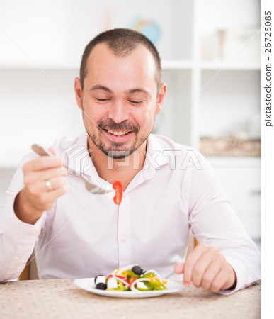 Positive young man eating greek salad Positive young man eating greek salad 26725085