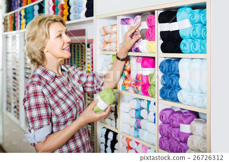 portrait of mature female customer standing next to shelf with knitting yarn in shop portrait of mature female customer standing next to shelf with knitting yarn in shop 26726312