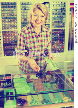 Portrait of female cashier standing at cash desk with scissors 26726351