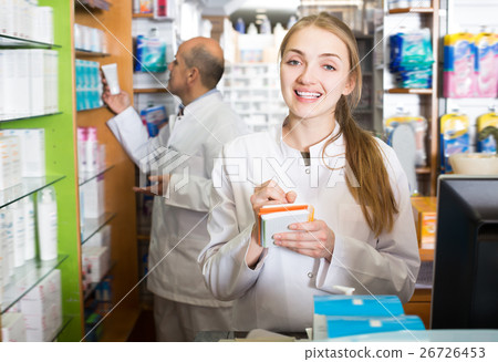 Young pharmacist and pharmacy technician helping 26726453