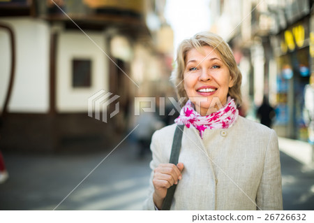 Senior woman standing on street in town. 26726632