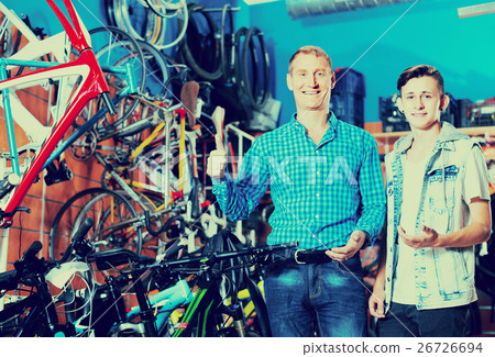 father with son choosing bike in store. 26726694