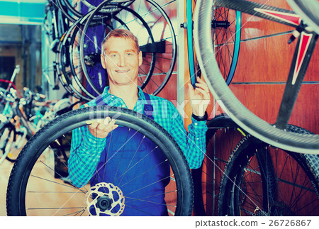 seller with bike wheel in hand in store. 26726867