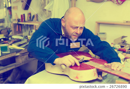 craftsman working with unfinished guitar 26726890