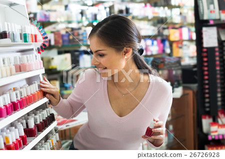 Beautiful young girl choosing nail polish Beautiful young girl choosing nail polish 26726928