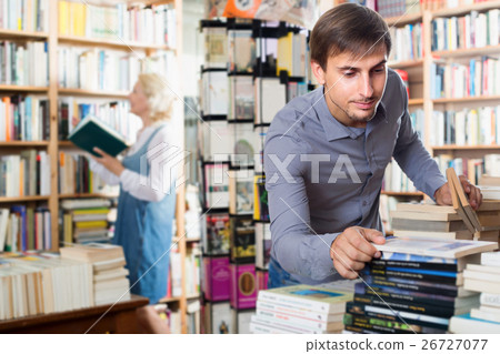 Young positive man looking for new book Young positive man looking for new book 26727077