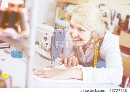 middle-aged female tailor using sewing machine middle-aged female tailor using sewing machine 26727318