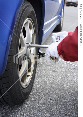People who loosen the wheel nut of a car People who loosen the wheel nut of a car 26729145