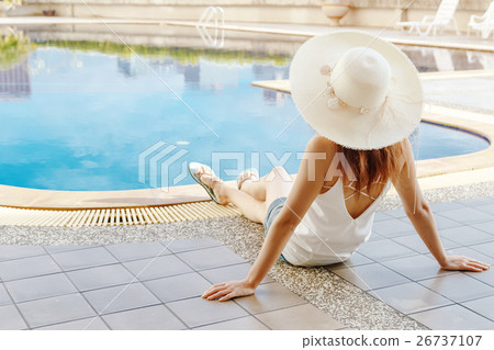 Young Asian woman sitting beside swimming pool Young Asian woman sitting beside swimming pool 26737107