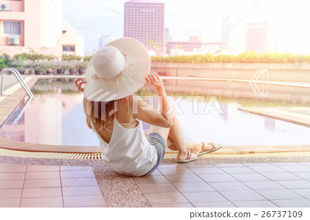 Young Asian woman sitting beside swimming pool Young Asian woman sitting beside swimming pool 26737109