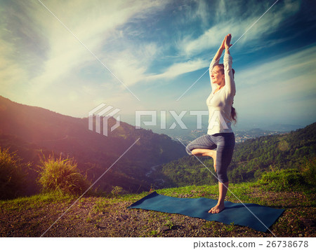 Woman in  yoga asana Vrikshasana tree pose in 26738678