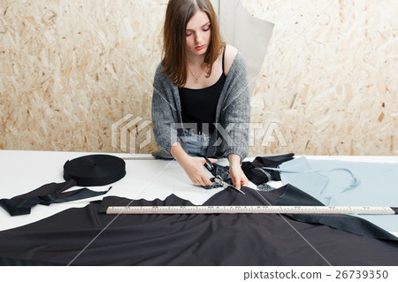 Young woman cutting black fabric in workshop 26739350