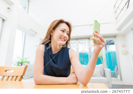 看智能手機的婦女在屋子裡 看智能手機的婦女在屋子裡 26745777