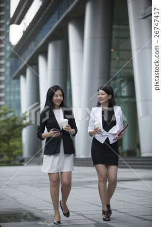 Two asian business woman talking outside. Two asian business woman talking outside. 26747417
